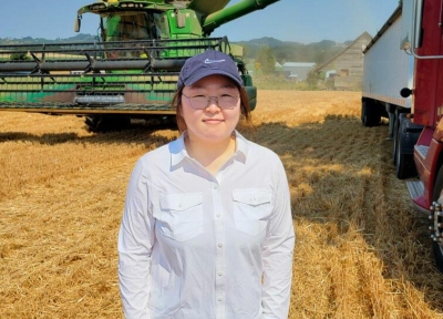 Hana You standing in front of a combine